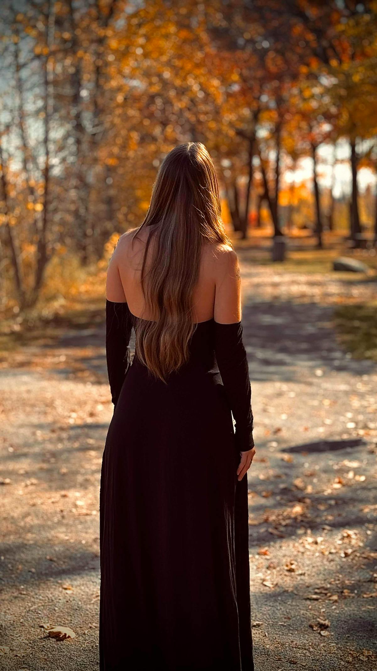 Woman in black dress walking through autumn park